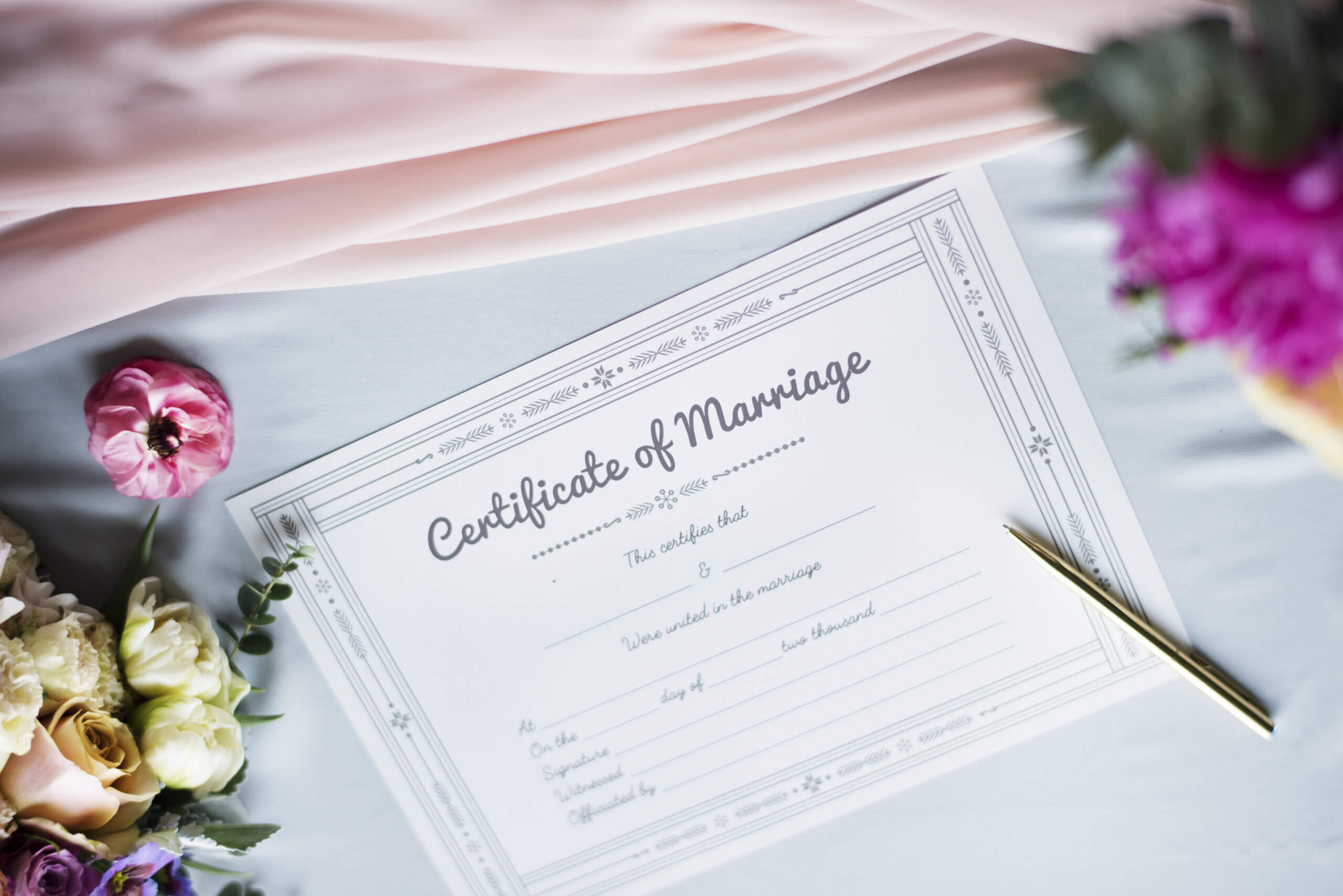 marriage certificate with flowers and pen and pink cloth