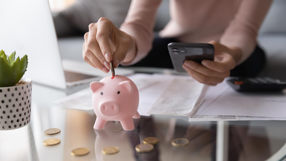 hand putting coin in piggy bank
