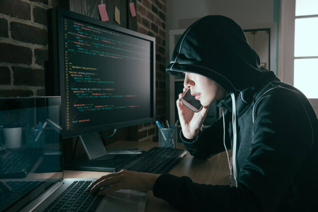 hacker in a hoodie on computer blackmailing someone on snapchat