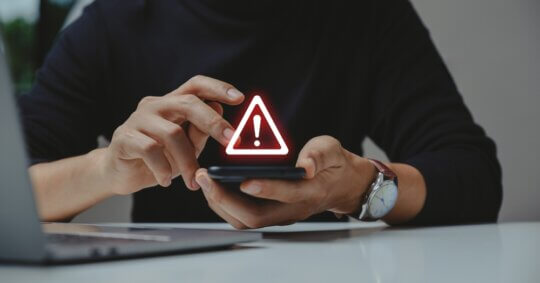 hand using phone with warning sign
