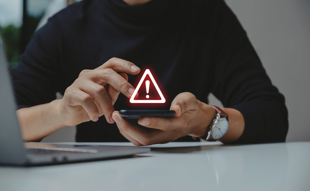 hand using phone with warning sign