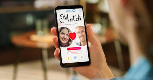 A man looking at a dating app on his smartphone.