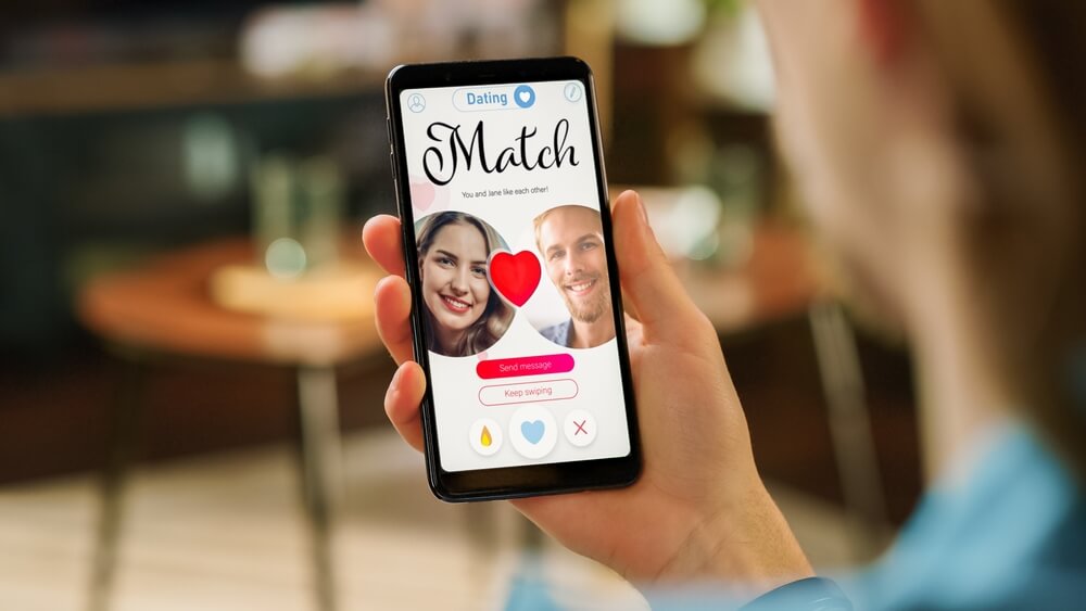 A man looking at a dating app on his smartphone.