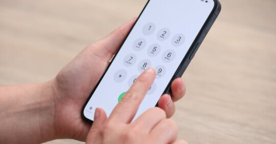 A woman dialing a phone number on a smartphone.