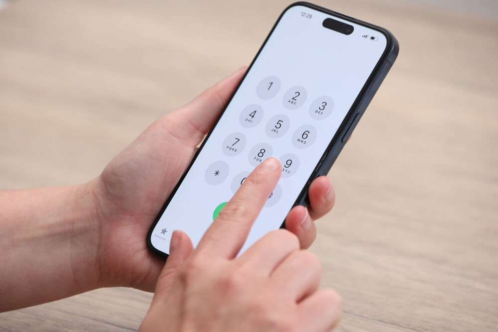 A woman dialing a phone number on a smartphone.