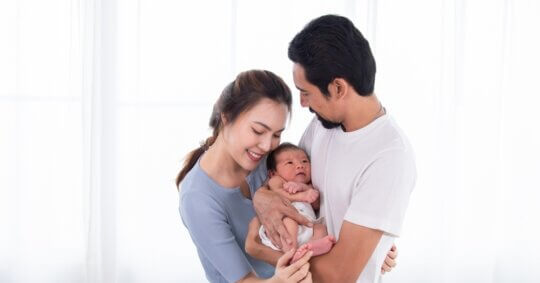 A couple, both birth parents, lovingly holding their newborn baby together.