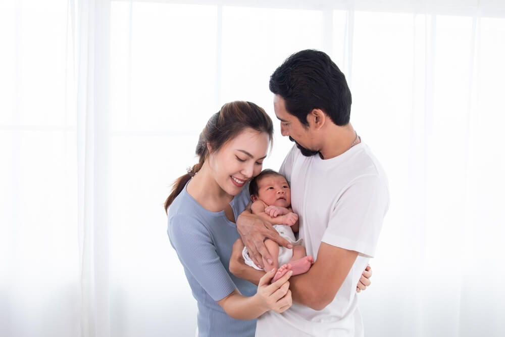 A couple, both birth parents, lovingly holding their newborn baby together.