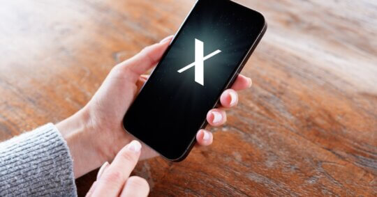 A person holding a phone and searching on the X app.