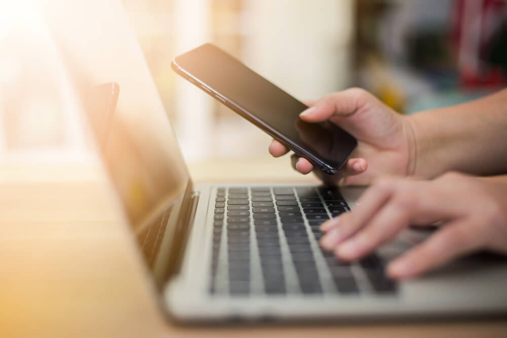 A person using his phone and laptop to search people on OnlyFans.