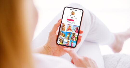A woman using her phone to check if people can see if you search them on Instagram.
