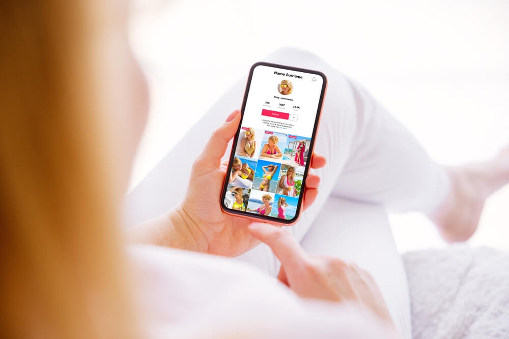 A woman using her phone to check if people can see if you search them on Instagram.