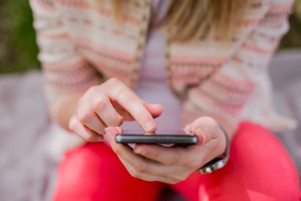 A woman using her phone to search for someone on Instagram.