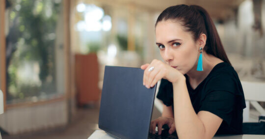 A woman using her laptop, wondering if people can people see what you search on WiFi.