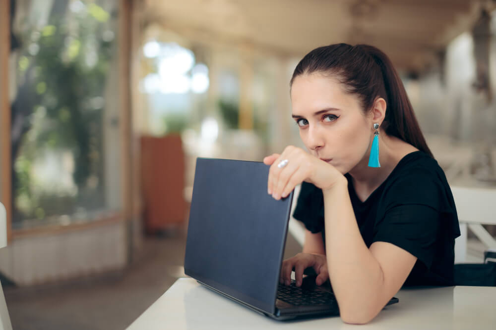 A woman using her laptop, wondering if people can people see what you search on WiFi.