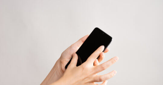 A person scrolling on her phone after learning how to do a Whatsapp phone number lookup.