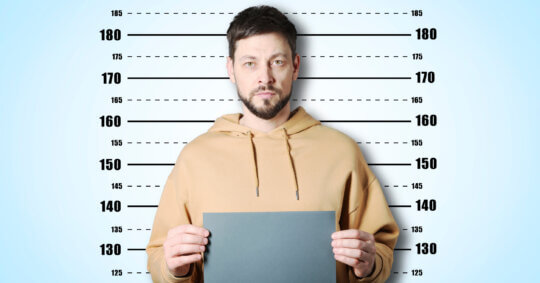 A man having his mugshot taken; he's wondering, "how long does a felony stay on your record?"