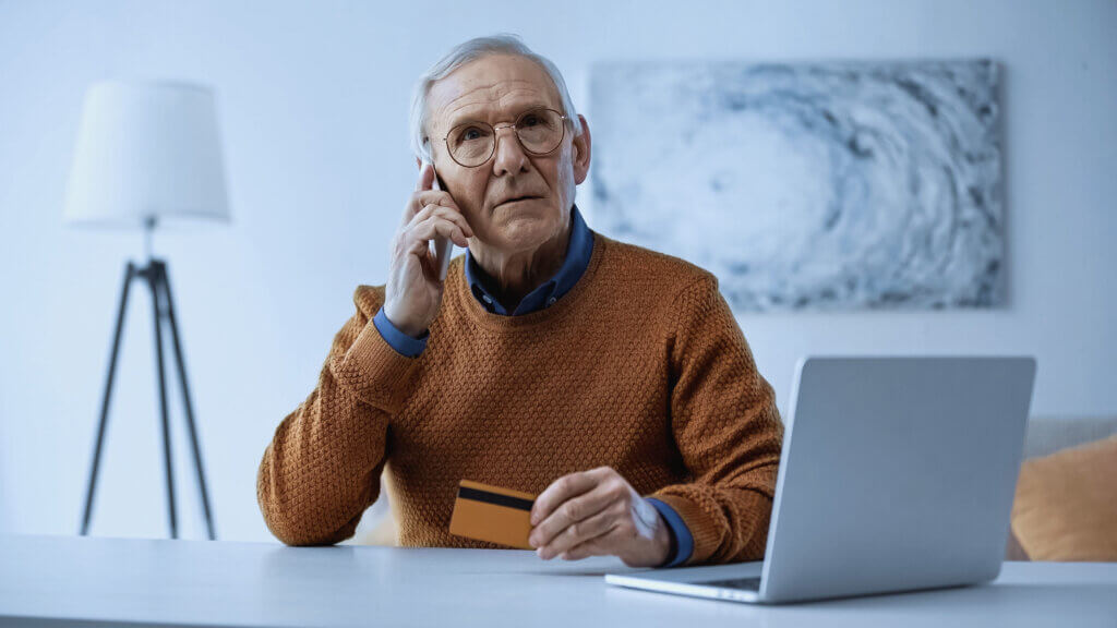 An old man sharing their credit card details over a phone call.