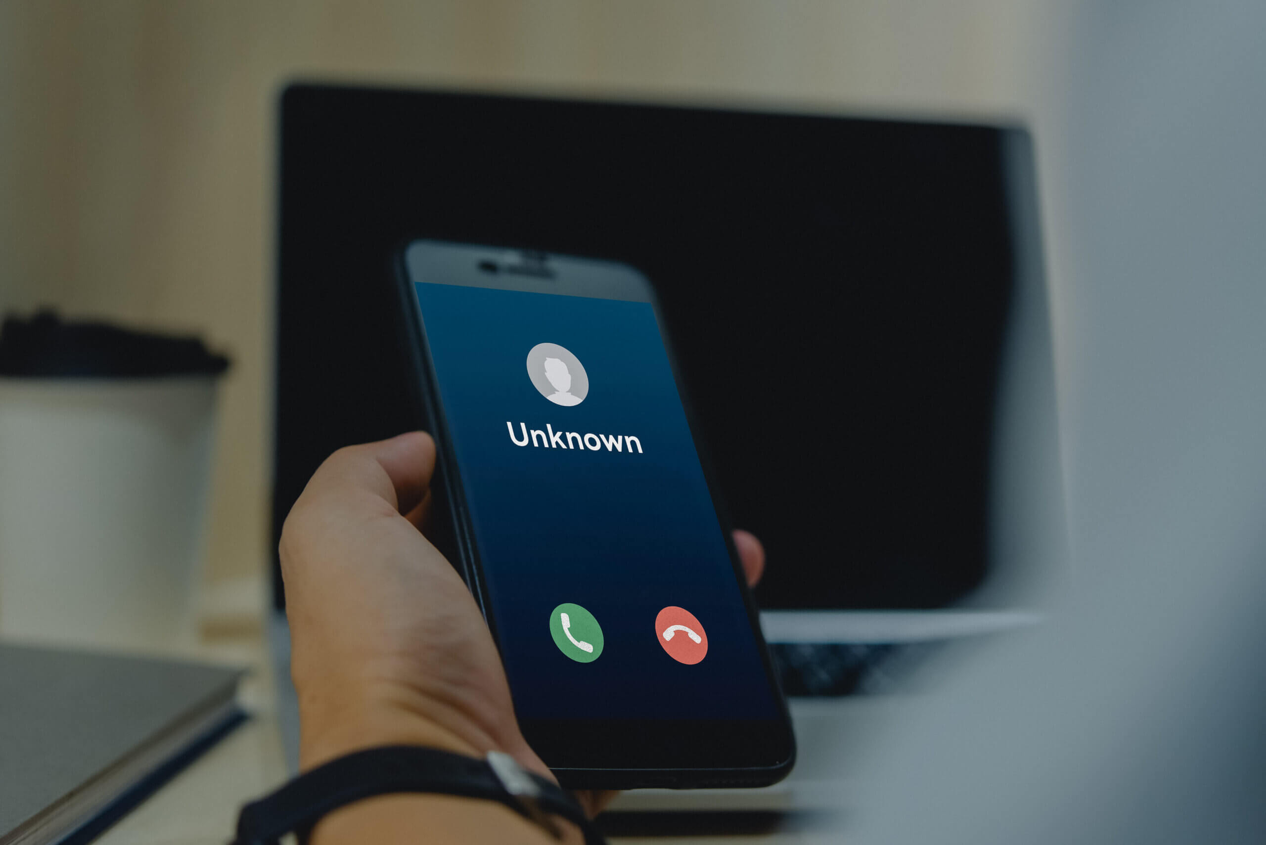 Close up of a phone screen with an incoming call labeled “unknown” through built-in service or third-party phone number scammer lookup tool.