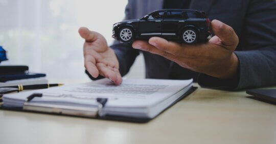 A person holding a toy car to illustrate traffic violations and offenses on the record.