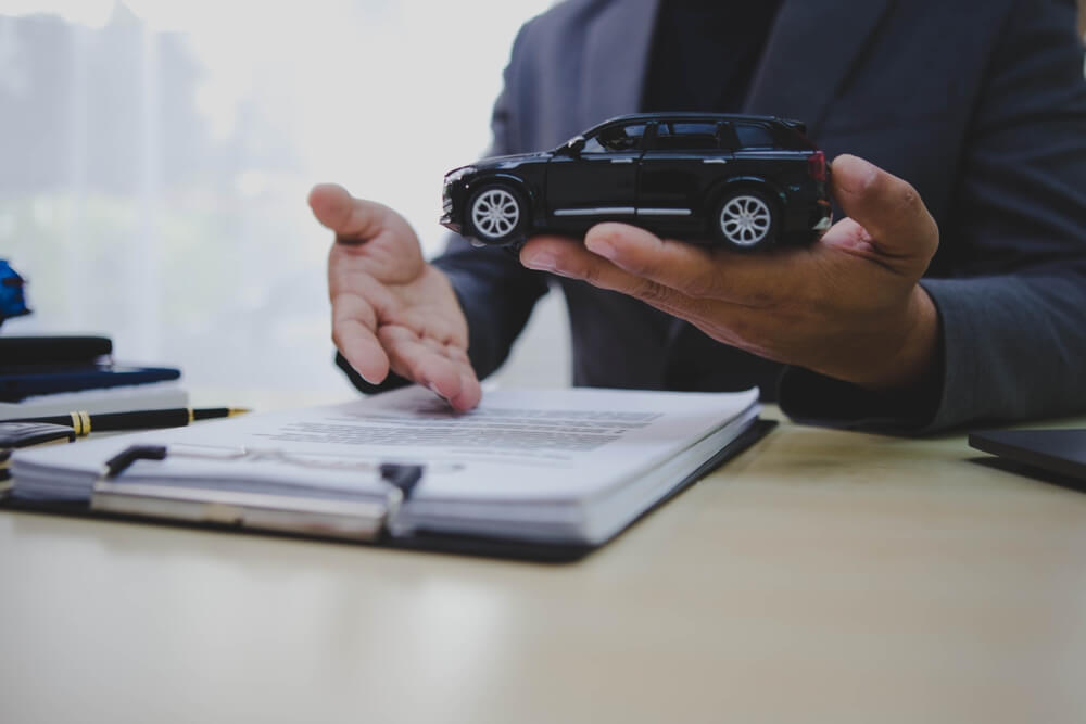 A person holding a toy car to illustrate traffic violations and offenses on the record.